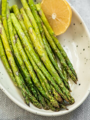 roasted asparagus in a bowl with half a lemon