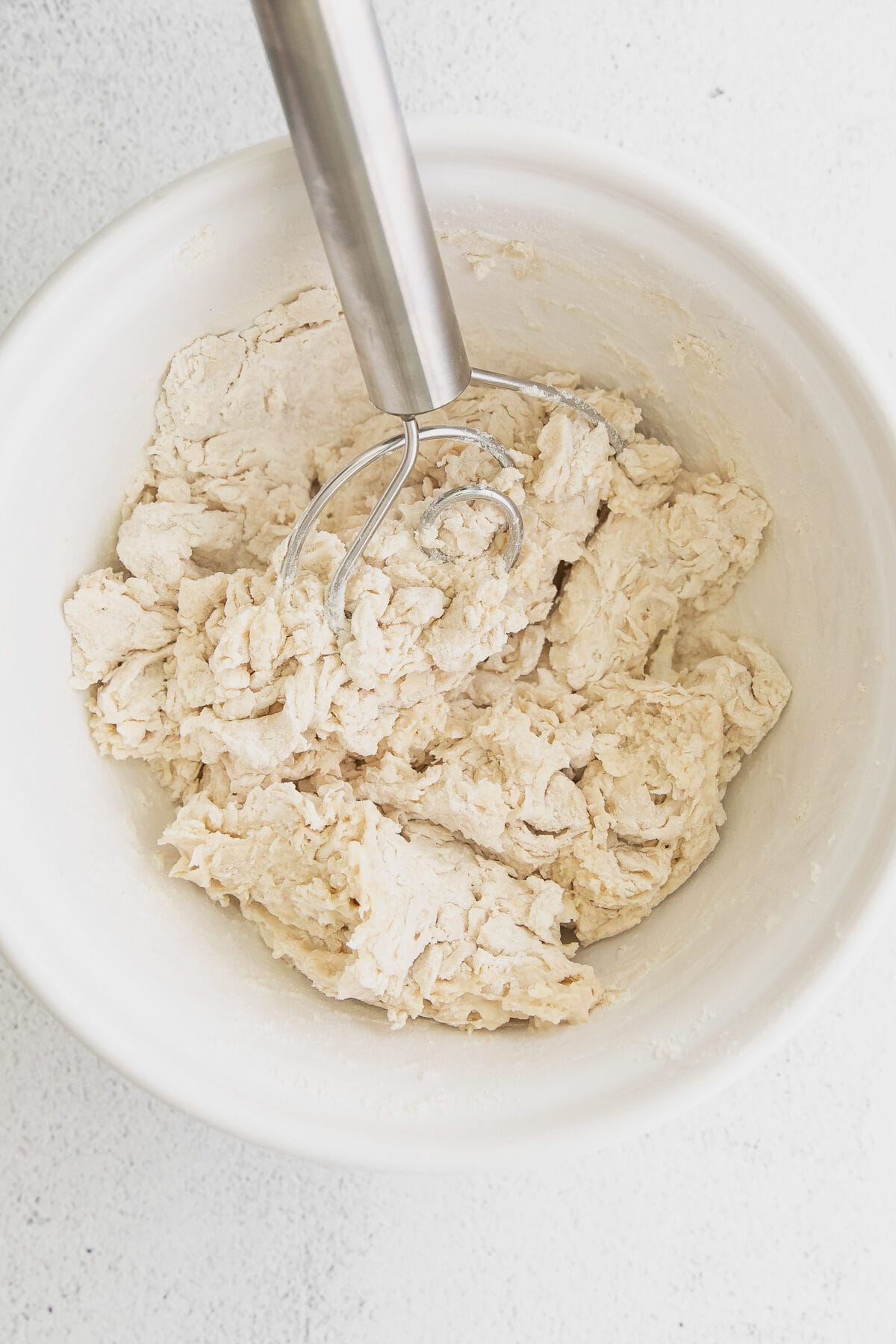 dough whisk with bagel dough in a white bowl.