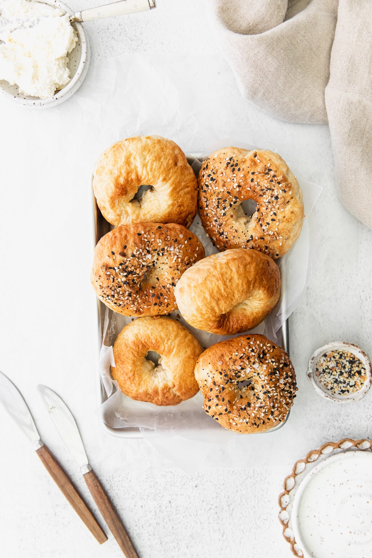 air fryer bagels on a tray with butter knives and seasoning to dress up the photo.