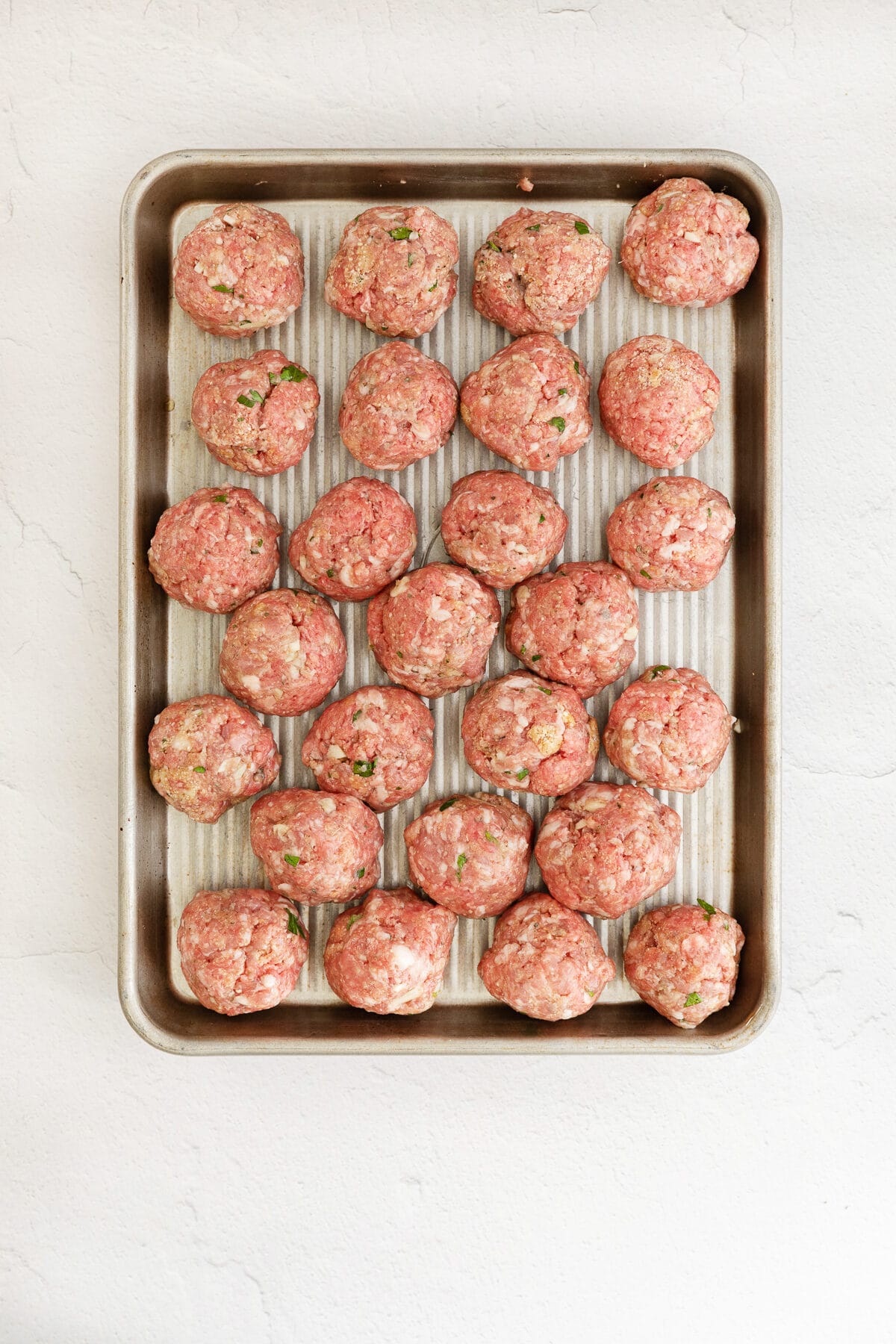 raw meatballs on a baking sheet.