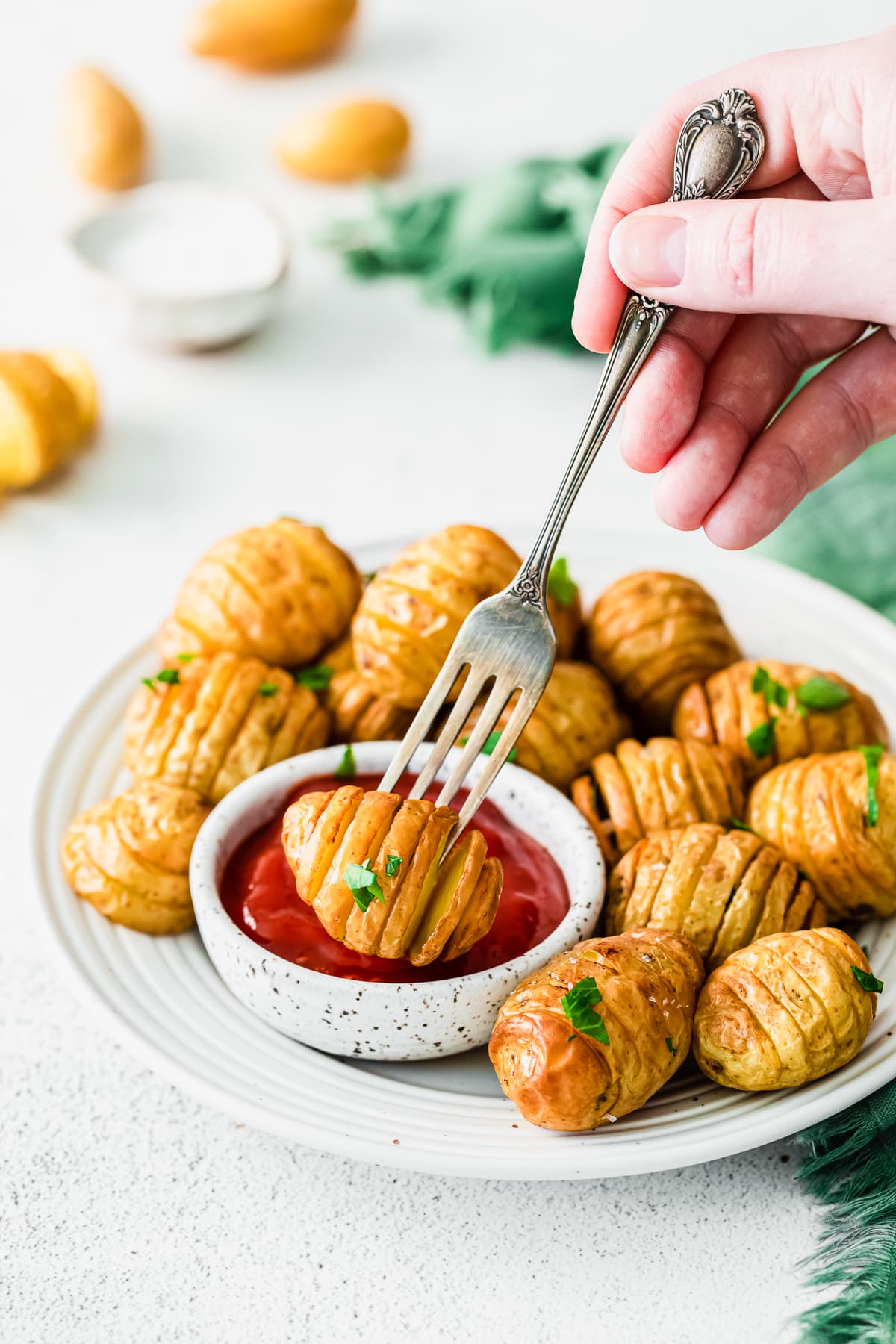 hand holding a fork grabbing a mini hasselback potato.