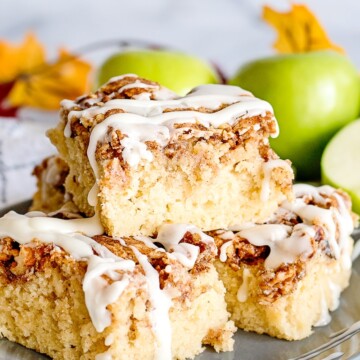 apple fritter breakfast cake sliced and stacked on a gray plate with granny smith apples in background