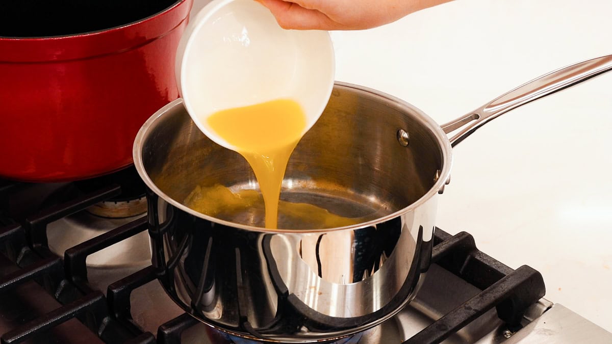 pouring juice into saucepan for ham glaze.