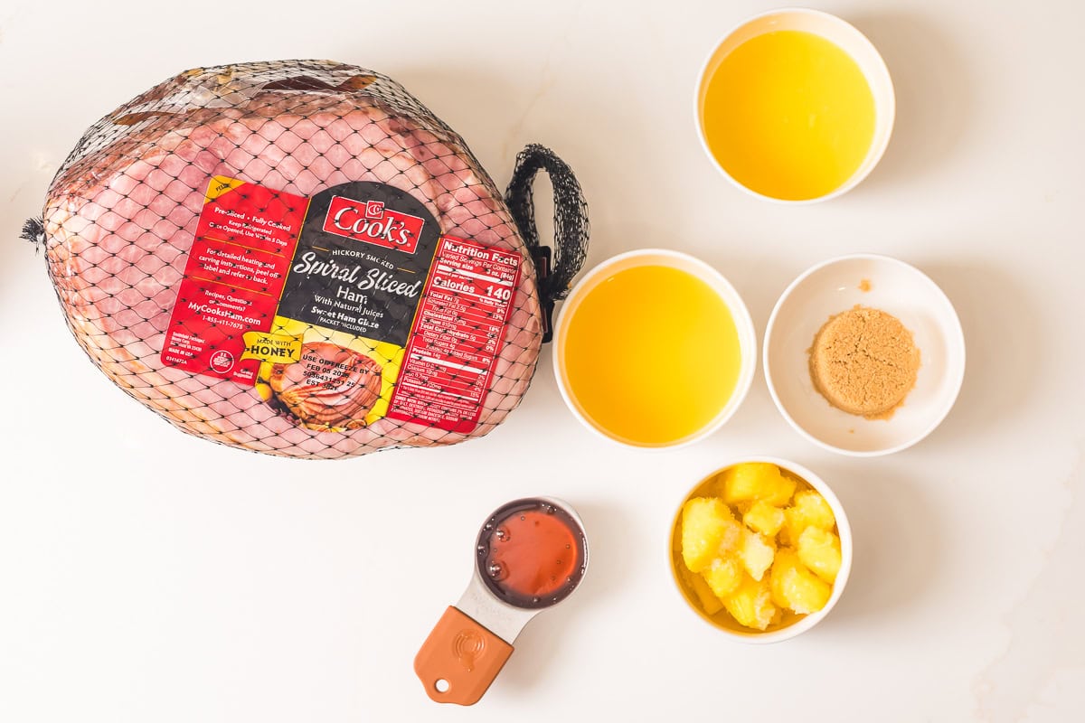 ingredients for baked ham in bowls with a large spiral ham to the left.