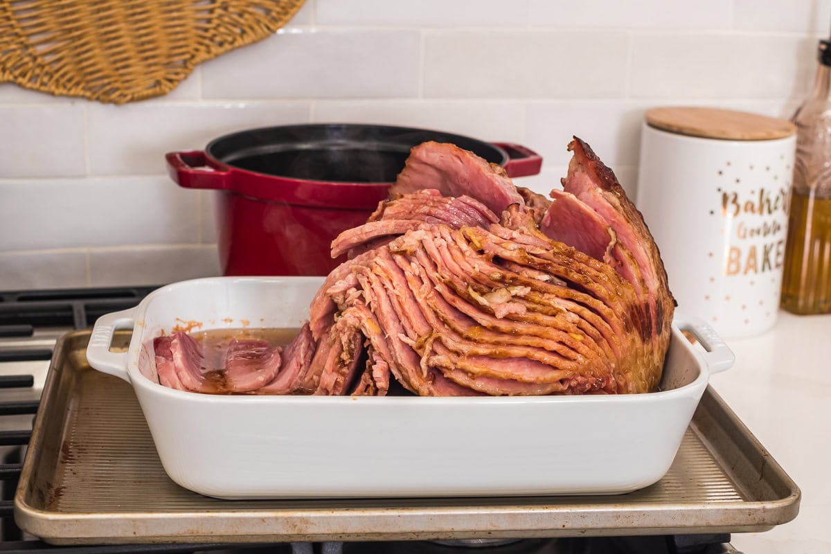 spiral ham in a white casserole dish almost done.