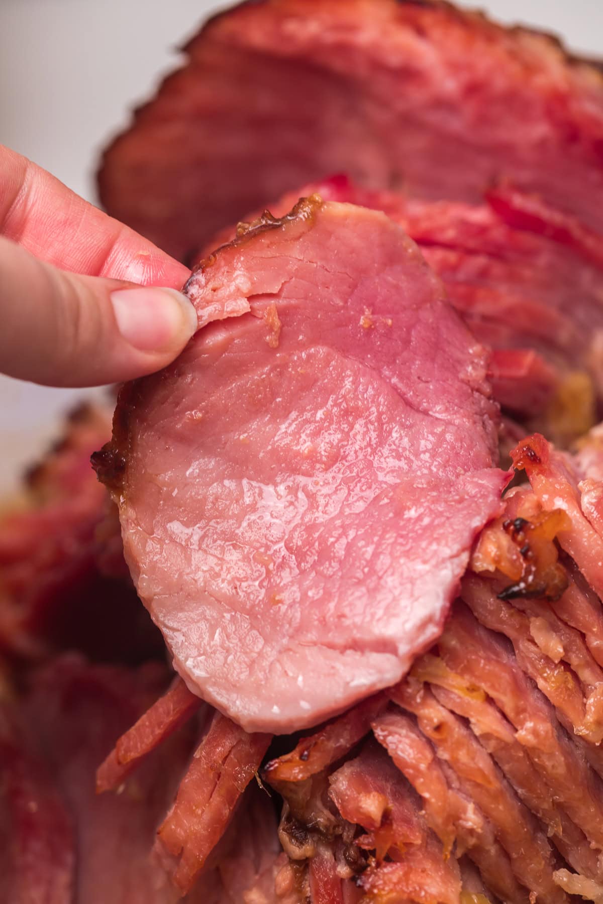 hand holding a piece of baked ham.