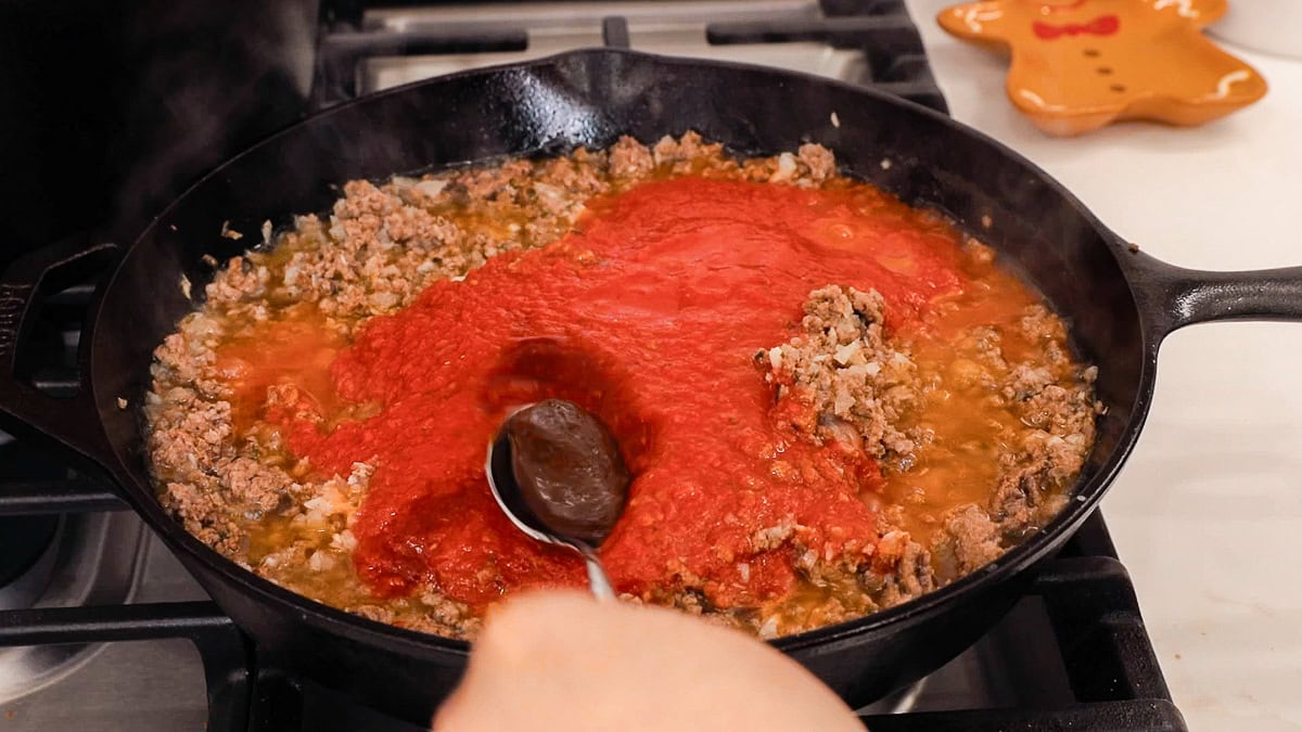 adding beef bouillon to meat sauce.