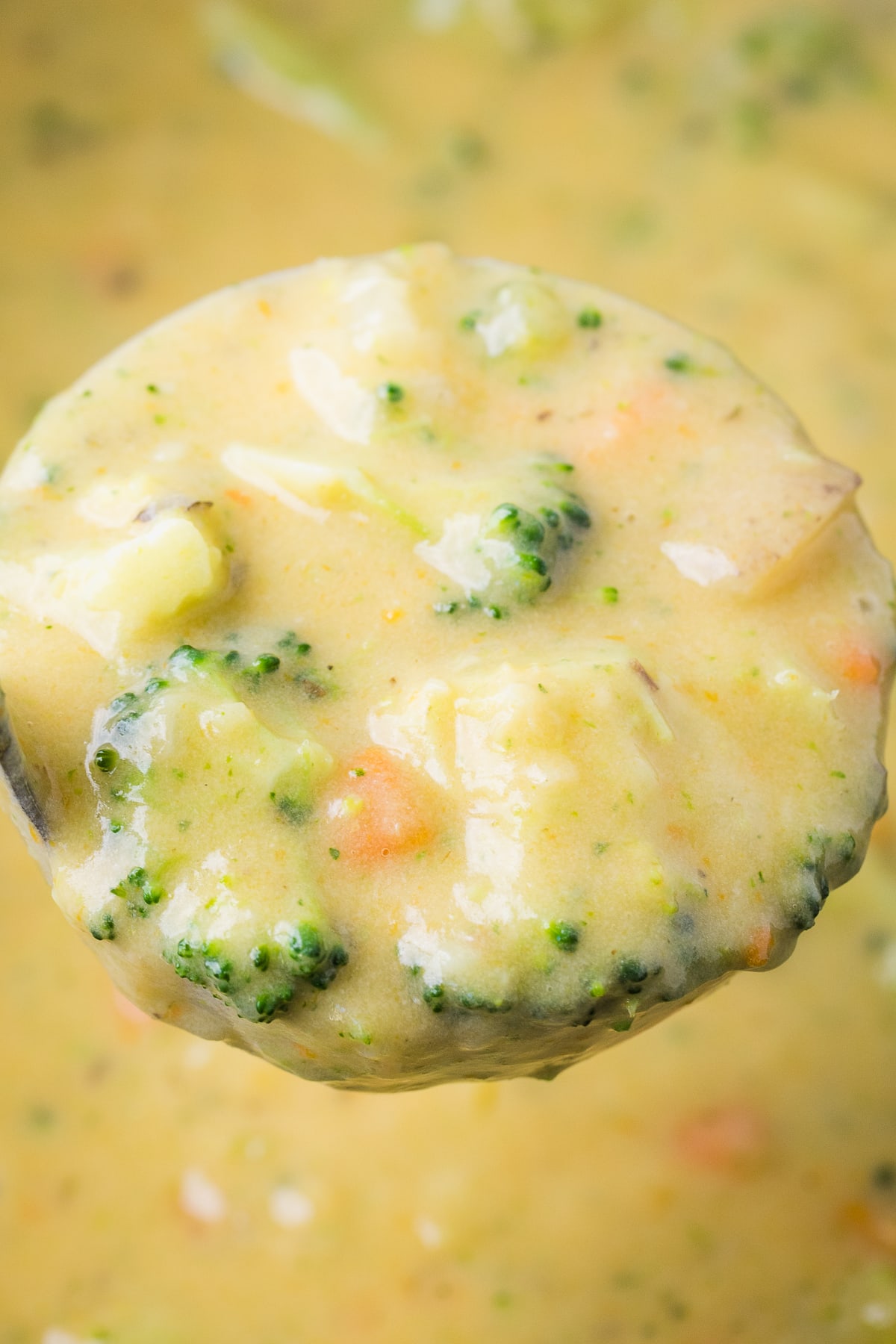 broccoli potato soup in a ladle over soup pot.