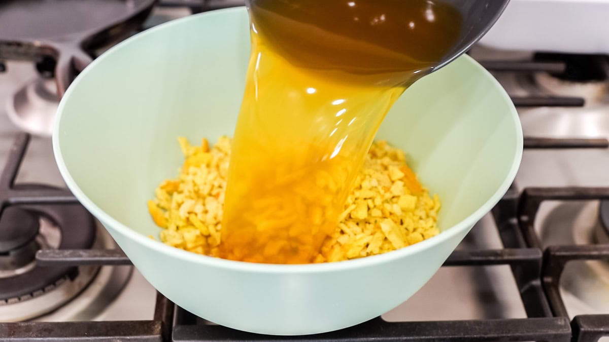 broth pouring over stuffing mix in a bowl.