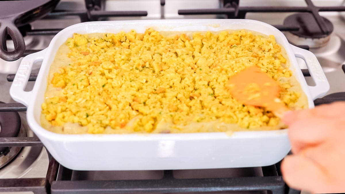 spreading stuffing onto casserole.