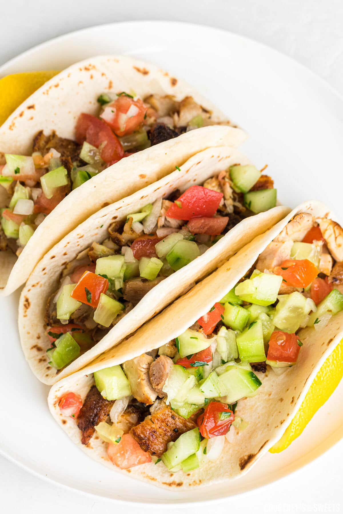 chicken tacos on a white plate with cucumber and tomato salsa