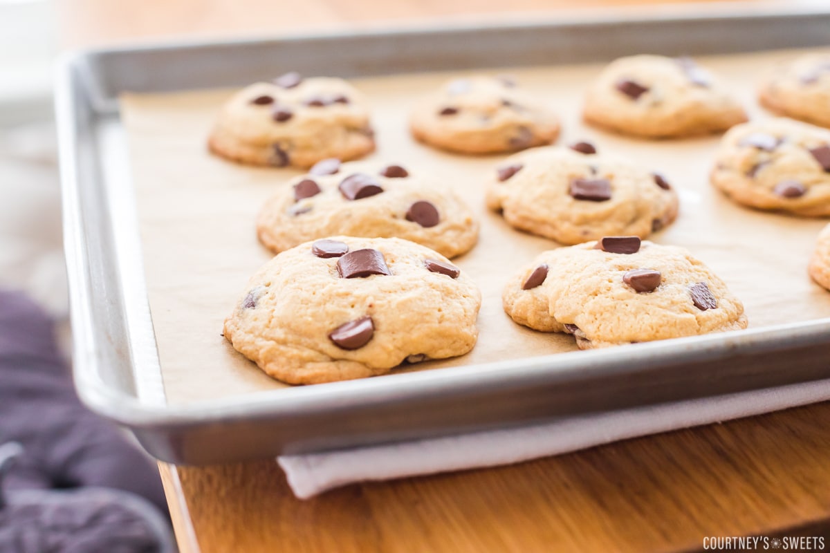 puffy cookies on a baking sheet on a towel lined table