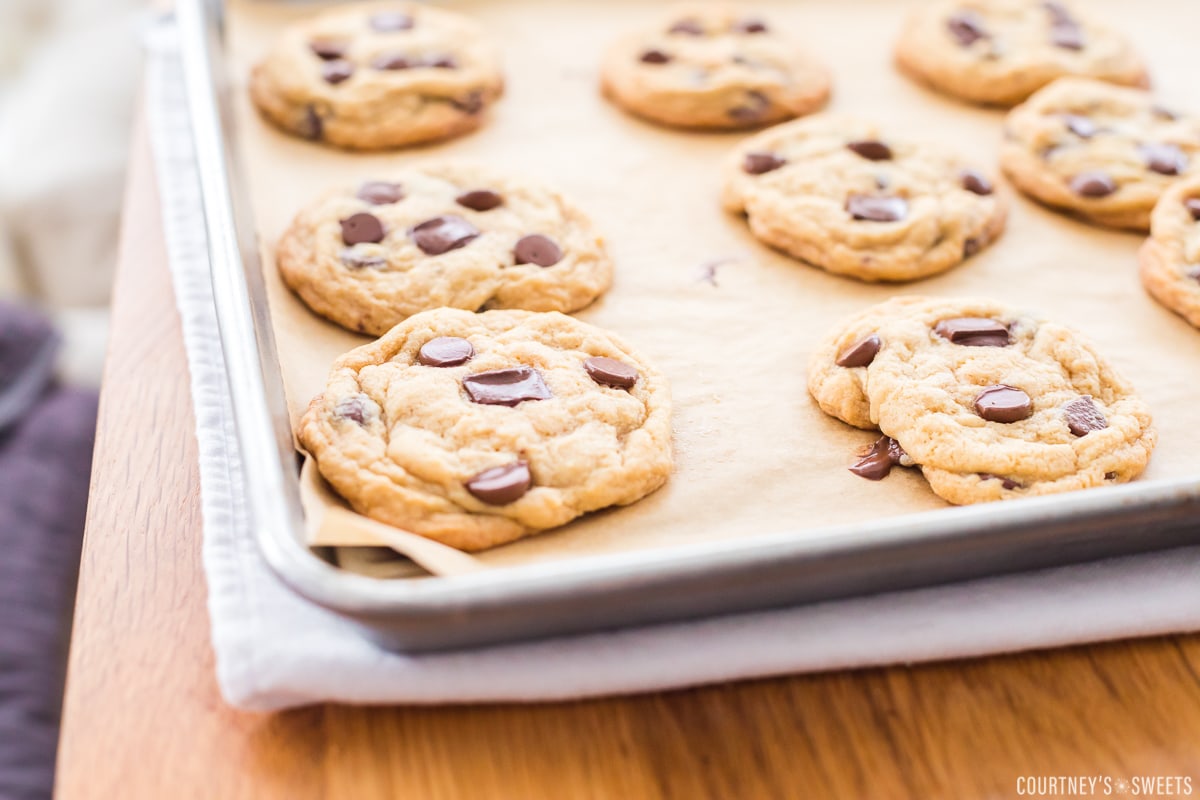 deflated chocolate chip cookies on a baking sheet on a towel lined table