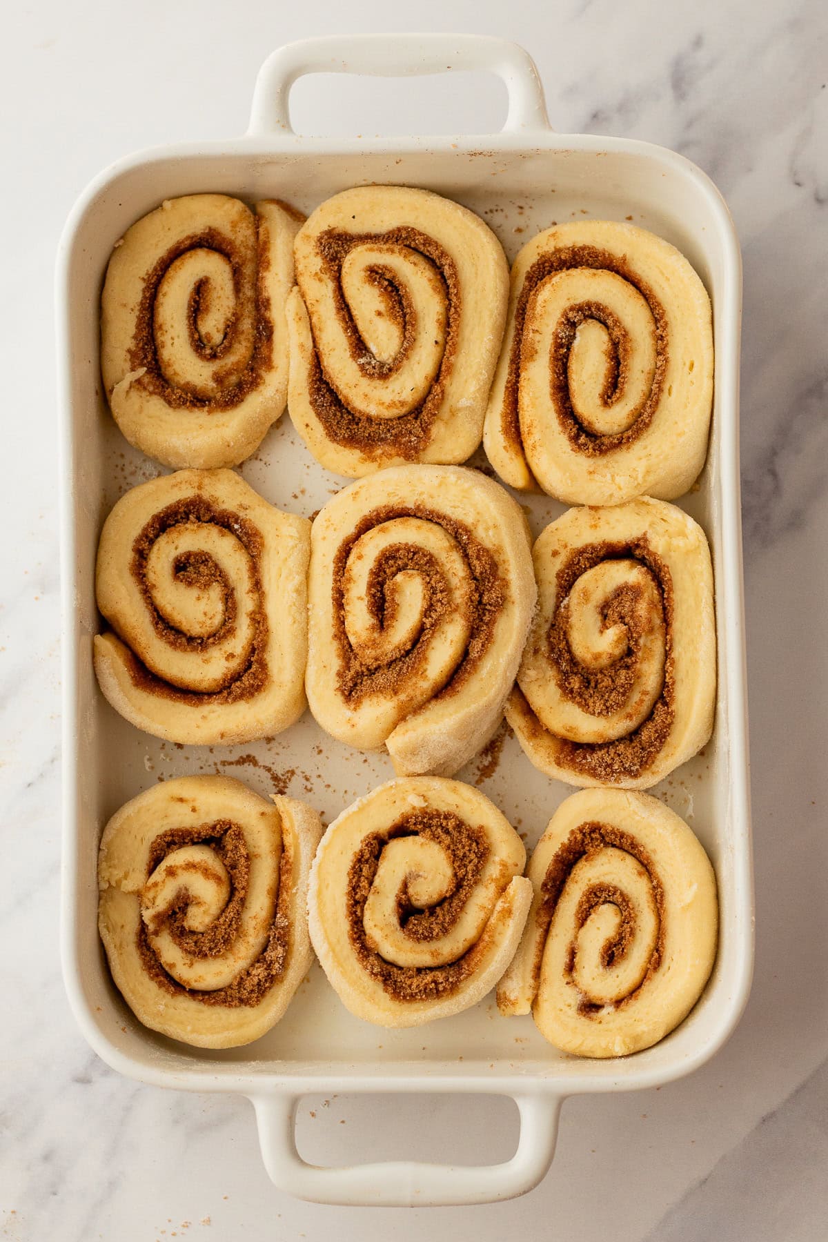 sliced cinnamon roll recipe in a baking dish ready to bake.