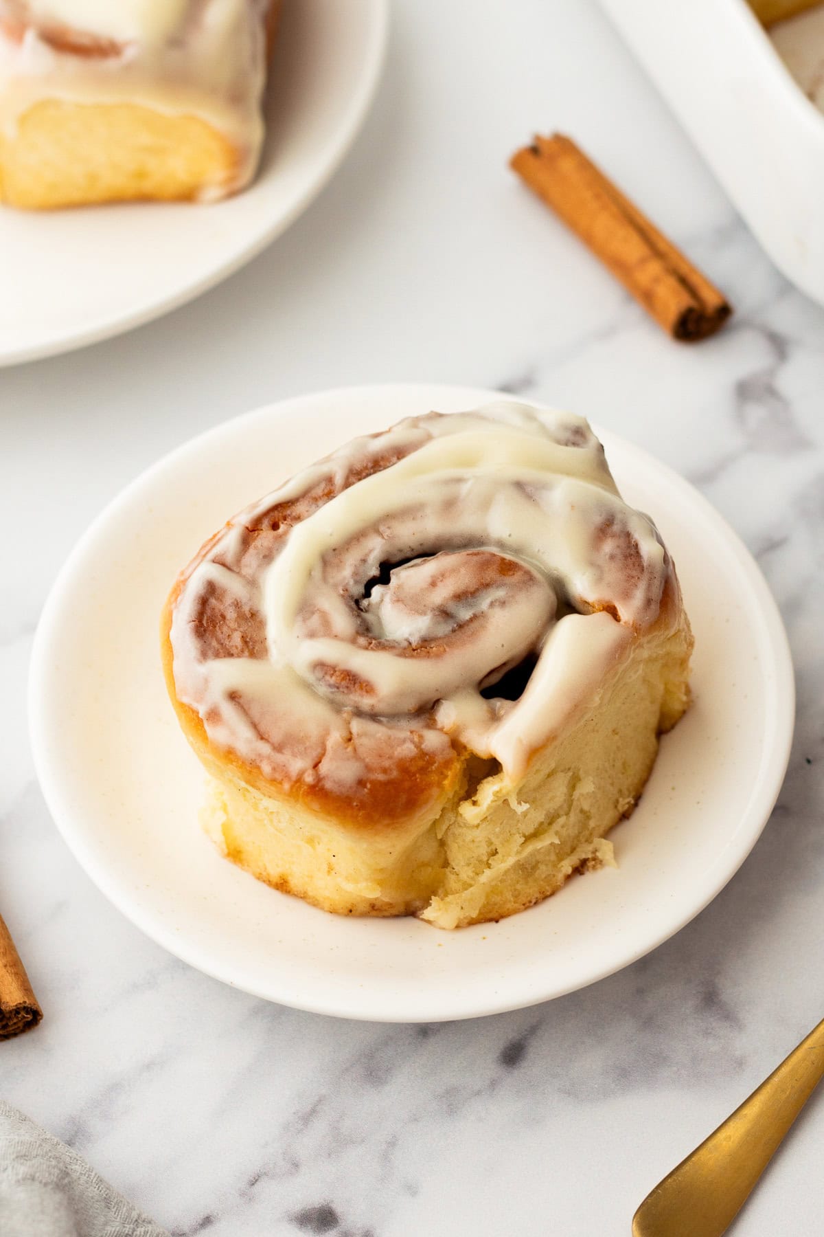 fresh baked cinnamon roll on a white plate.