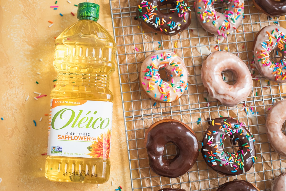 Oléico Safflower Oil, 32 oz. bottle next to a cooling rack with donuts.