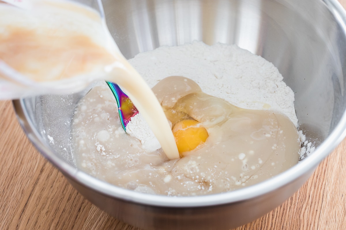 wet ingredients pouring into a bowl with dry ingredients.