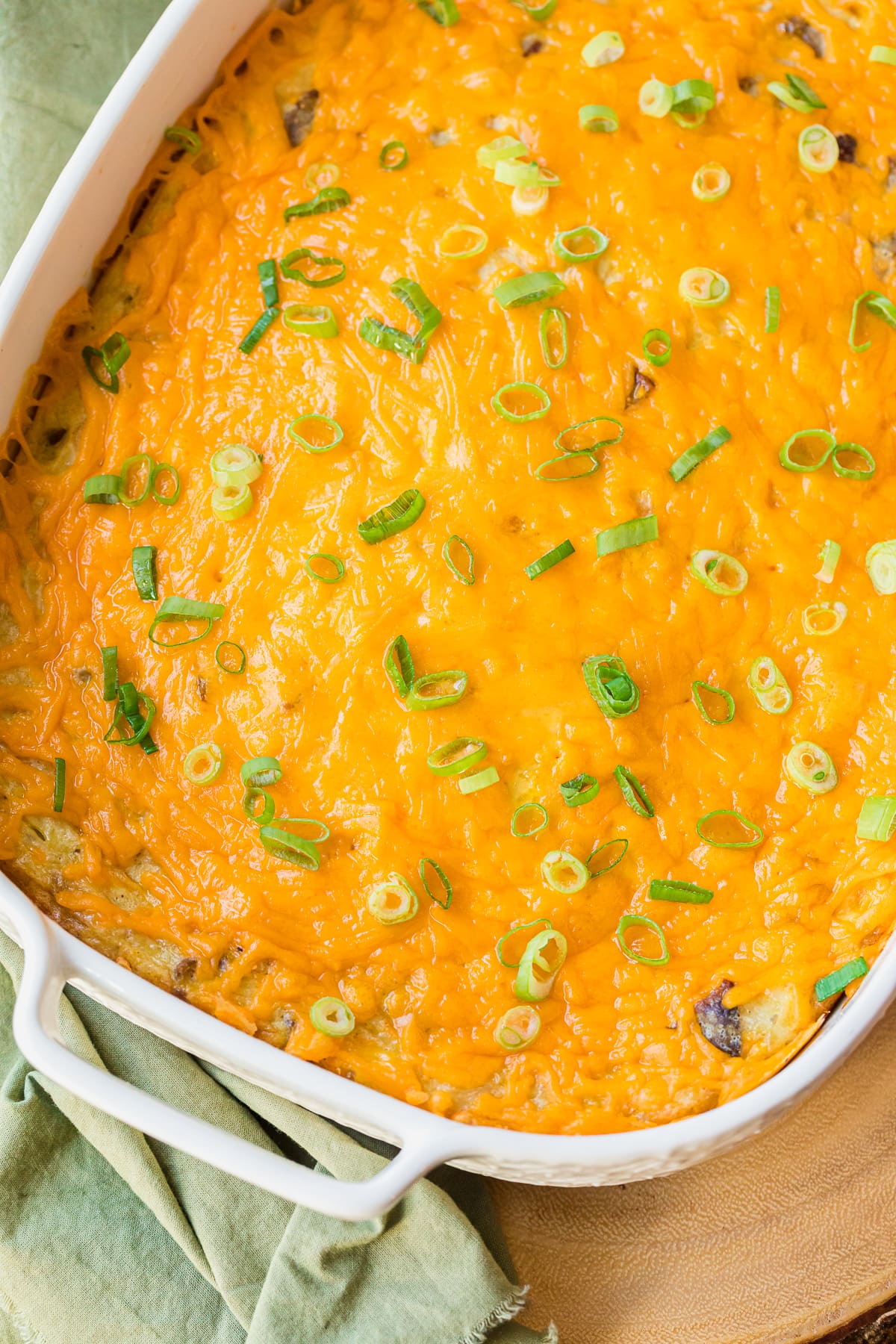 flay lay photo of easy breakfast casserole in a white casserole dish with melted cheese and sliced green onions.