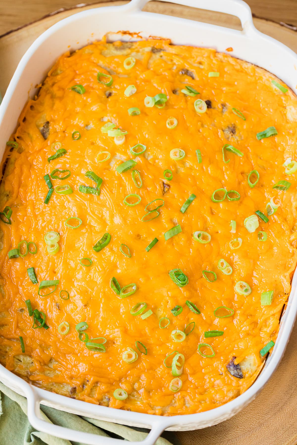 overhead photo of easy breakfast casserole in a white casserole dish with melted cheese and sliced green onions.