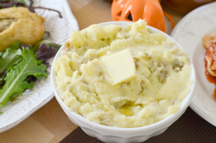 mashed potatoes in a white bowl with a tab of butter on top.