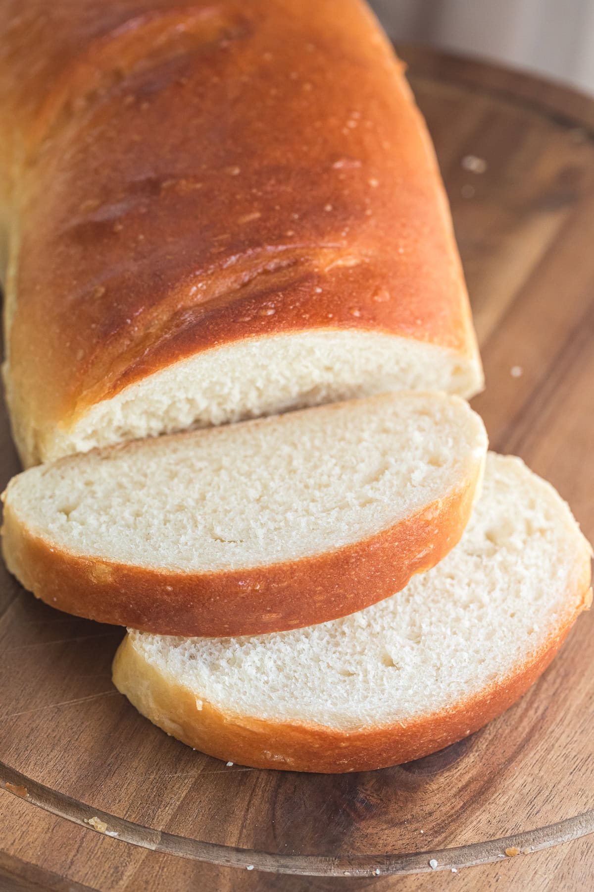 two fresh slices of french bread with the french bread loaf behind it.