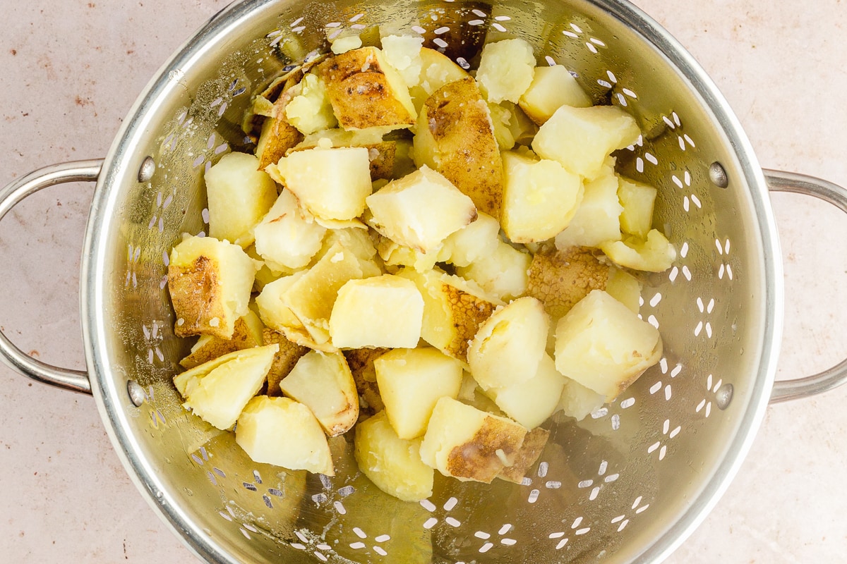 potatoes draining in a stainless steel colander.