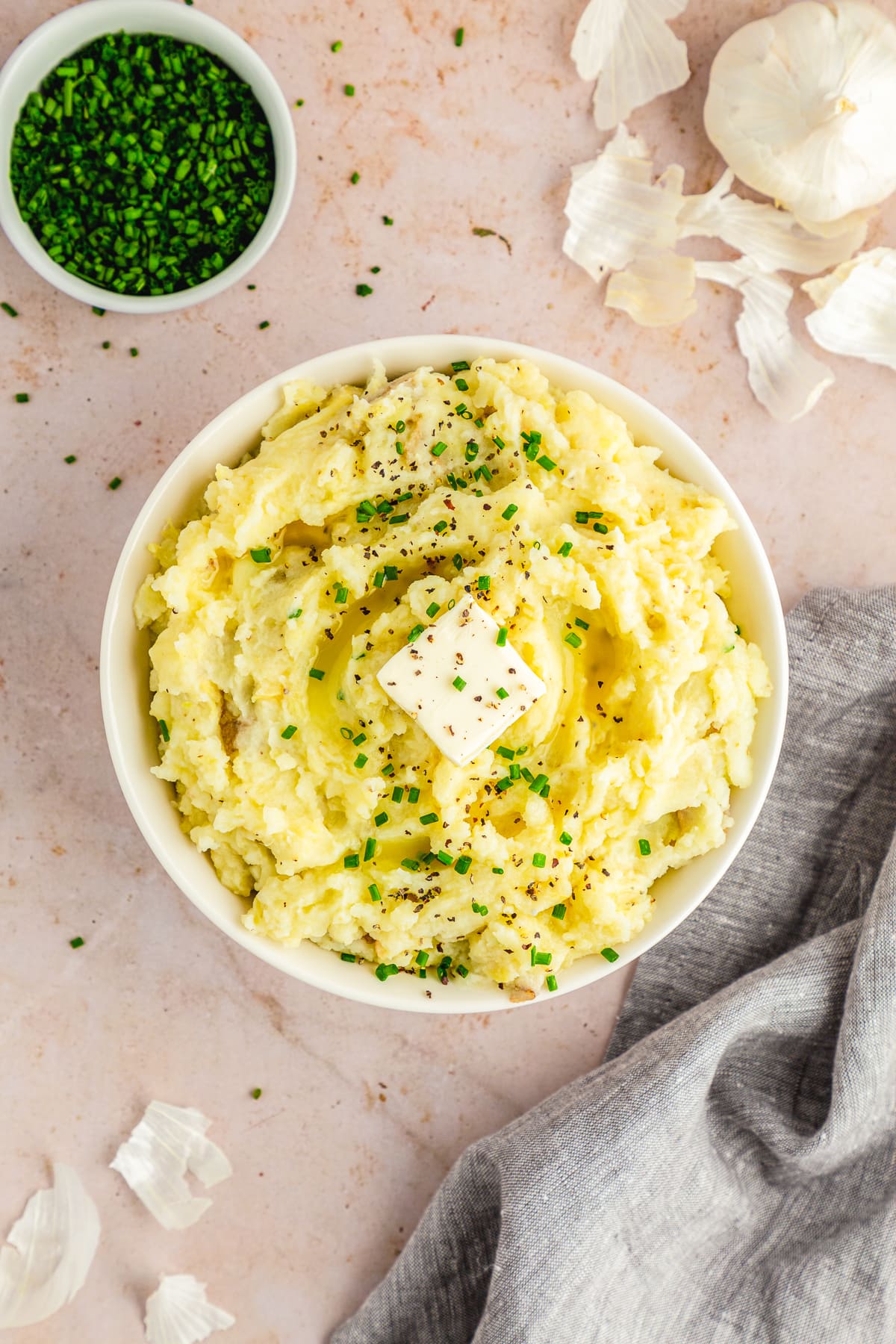 garlic mashed potatoes garnished with chives and a pat of vegan butter overhead photo.