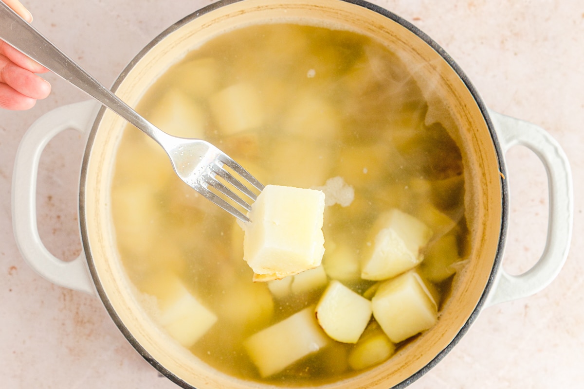 fork with a potato on it showing fork tender potatoes for mashing.