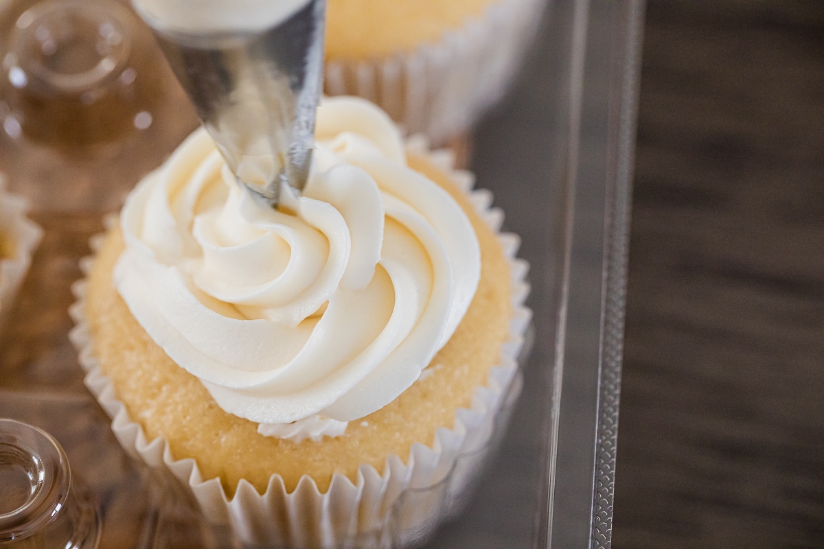 piping frosting onto gender reveal cupcakes.
