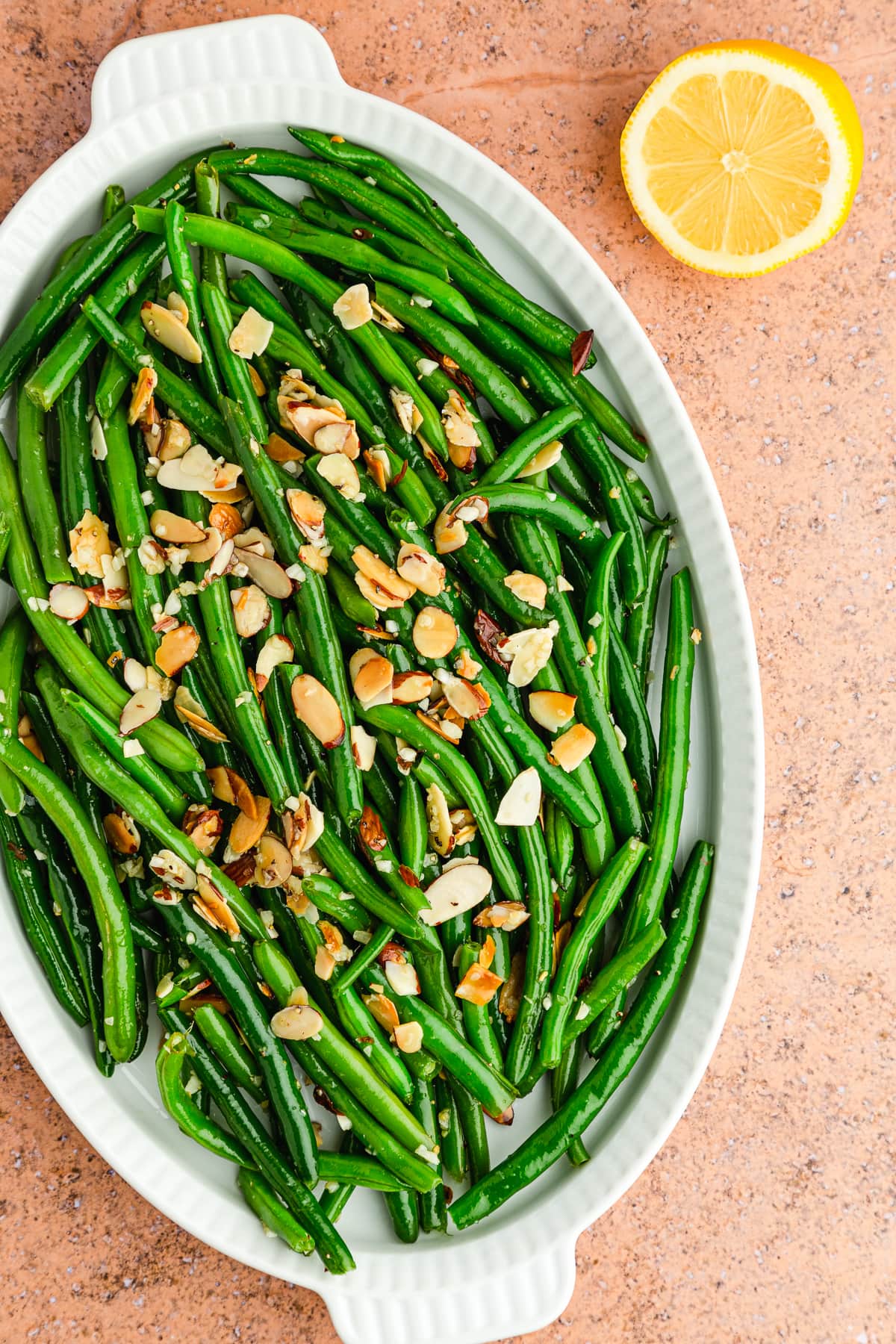 homemade green beans almondine on a white platter.