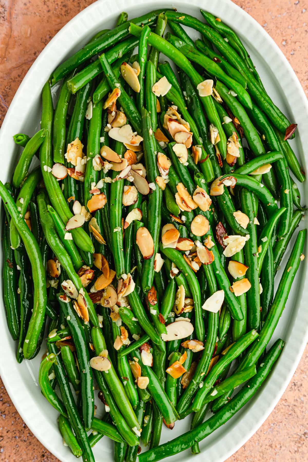 close up of green beans almondine on a white platter.