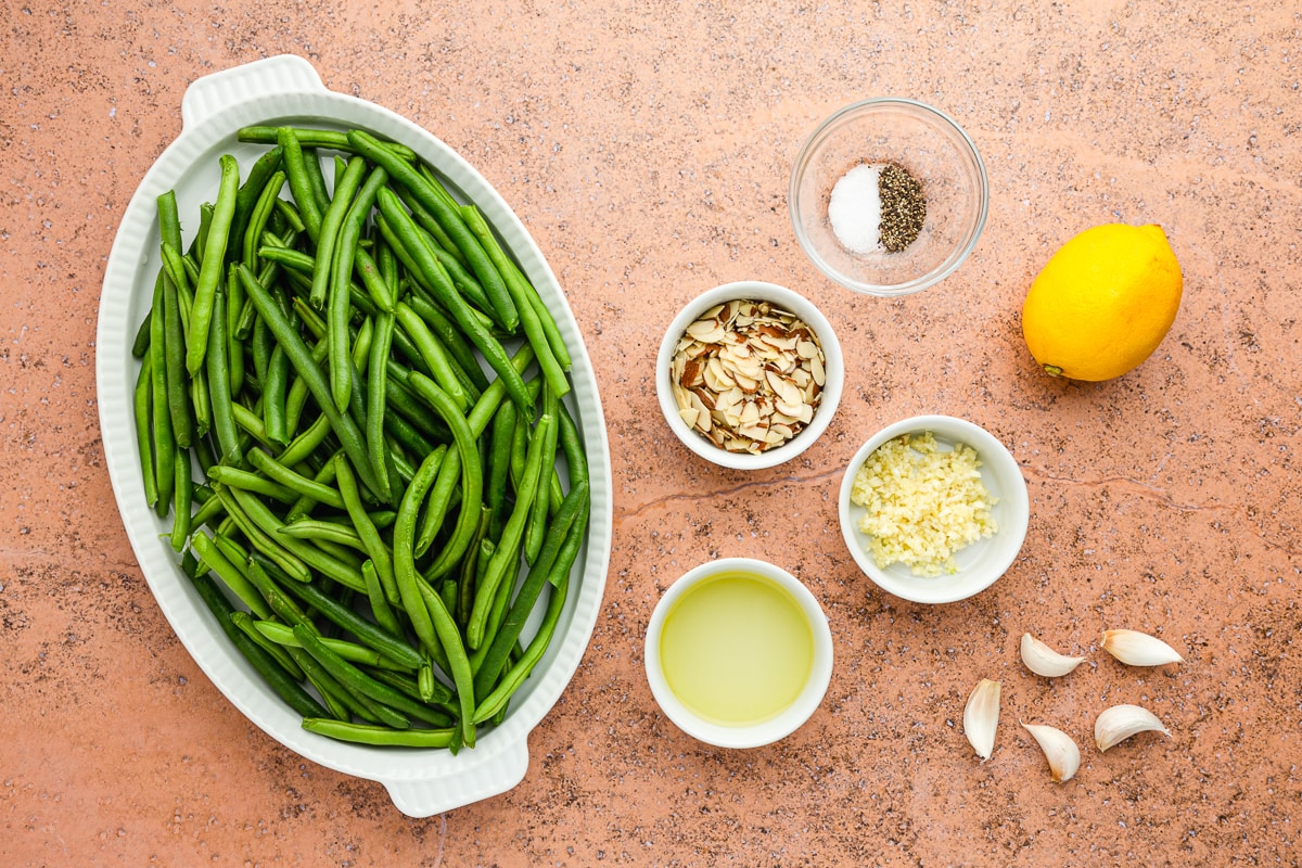 raw green beans on a platter with bowls of ingredients around it.