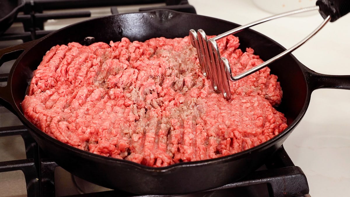 raw ground beef in cast iron skillet.