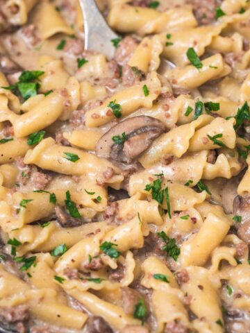 ground beef stroganoff in a cast iron skillet with a serving spoon.