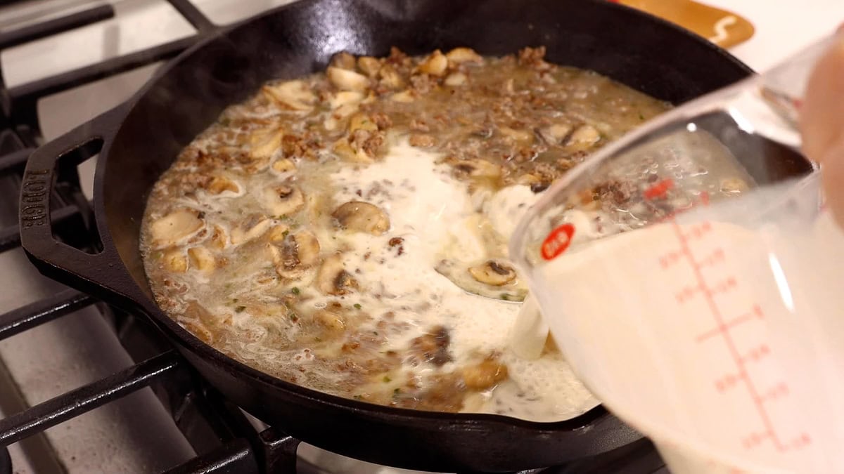 adding milk to ground beef mixture in skillet.
