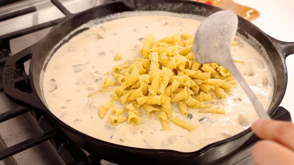 adding pasta to beef stroganoff mixture in skillet.