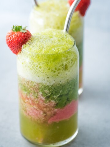 layered smoothie with seltzer in a glass with strawberry and stainless steel straws for mocktails