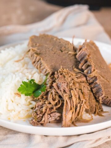 instant pot bottom round roast beef served with white rice on a plate.