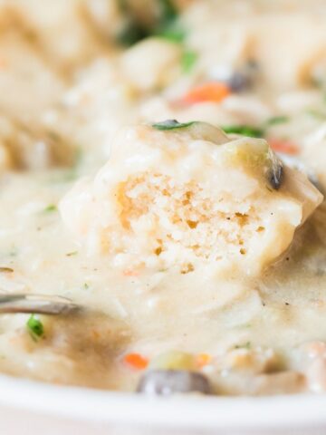 instant pot chicken and dumplings with a cut open dumpling in a white bowl.