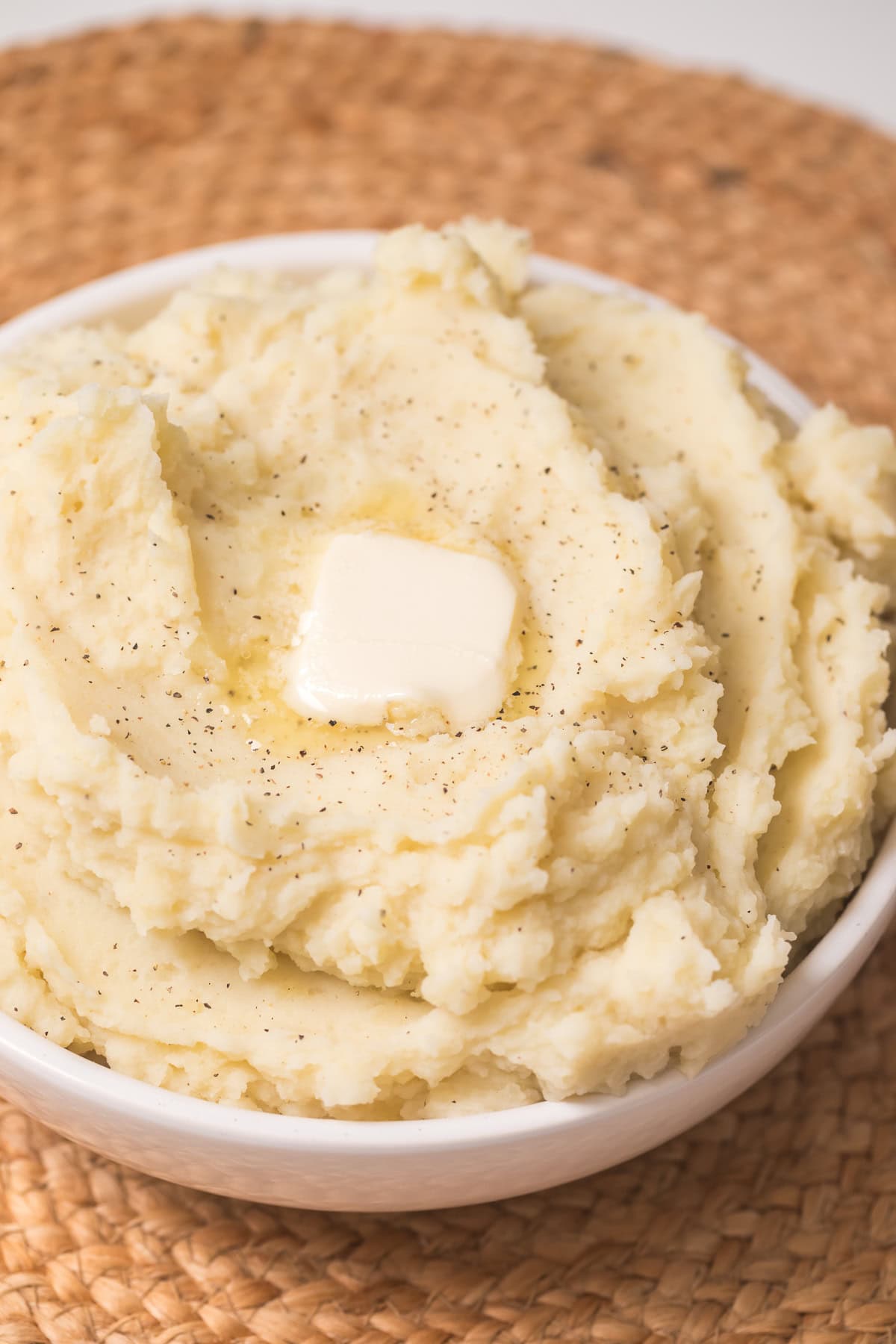 close up photo of instant pot mashed potatoes in a low white bowl with a tab of butter on the top.