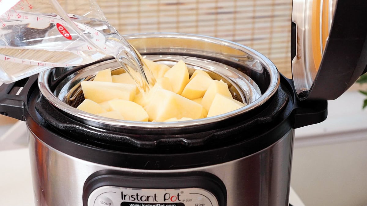 pouring water into instant pot with potatoes.