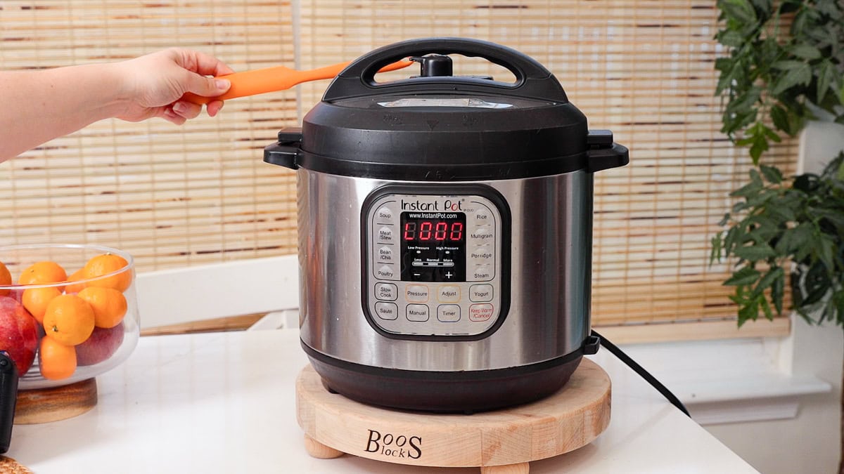 hand holding long spatula to carefully quick release steam from the instant pot.