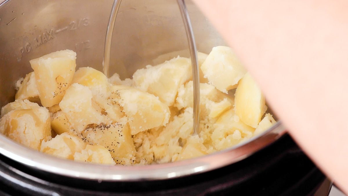 hand mashing potatoes in the instant pot.