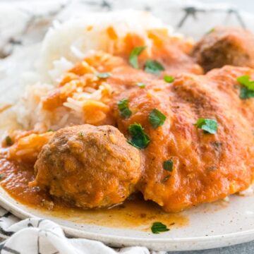 grandma's chicken friccassee with meatballs on a plate resting on a white napkin with black lines.