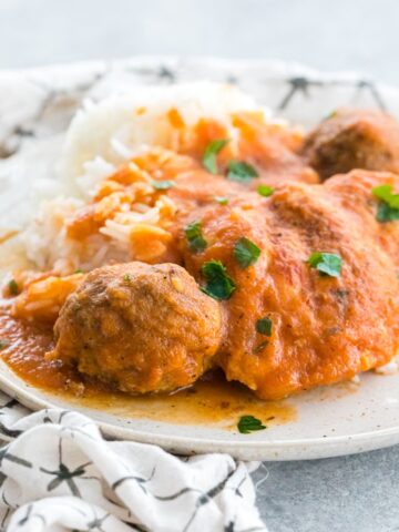 grandma's chicken friccassee with meatballs on a plate resting on a white napkin with black lines.