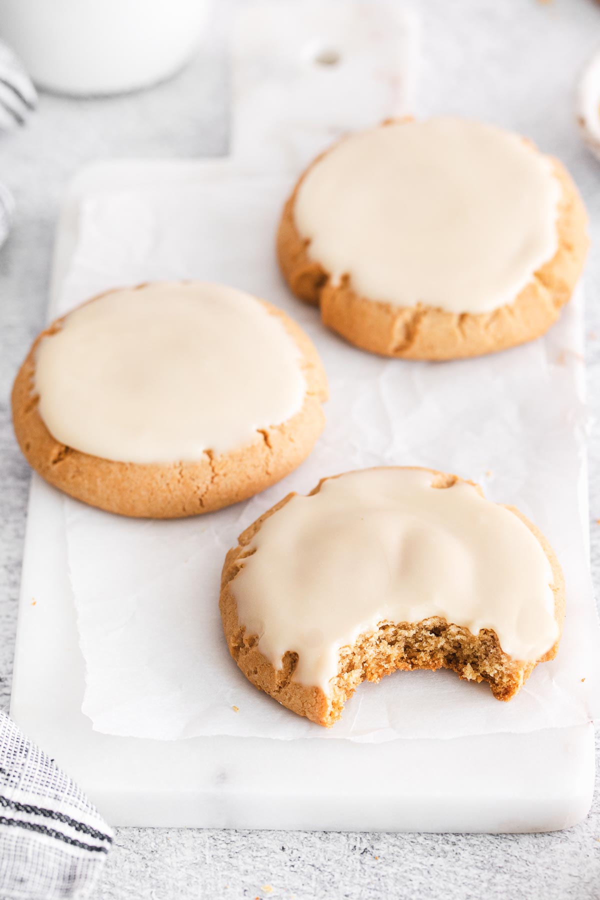 overhead photo of maple cookies on a piece of white parchment paper one with a bite taken out.