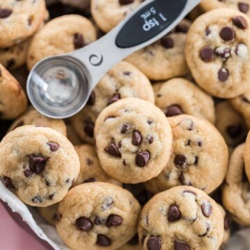 mini chocolate chip cookies in a chocolate molded heart with a teaspoon measuring spoon to show size on top.