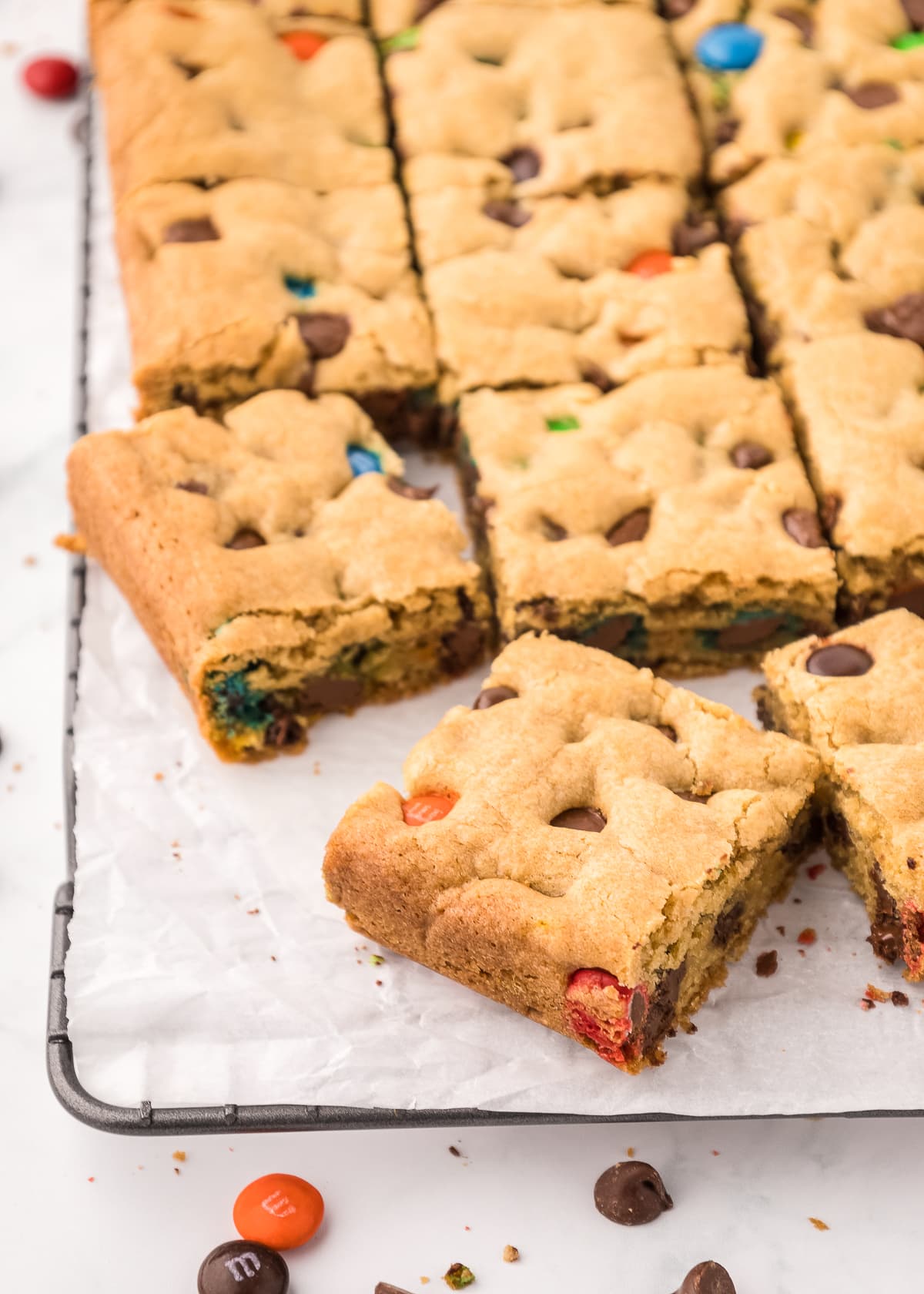 overhead of m&m chocolate chip cookie bars sliced on a piece of parchment paper.