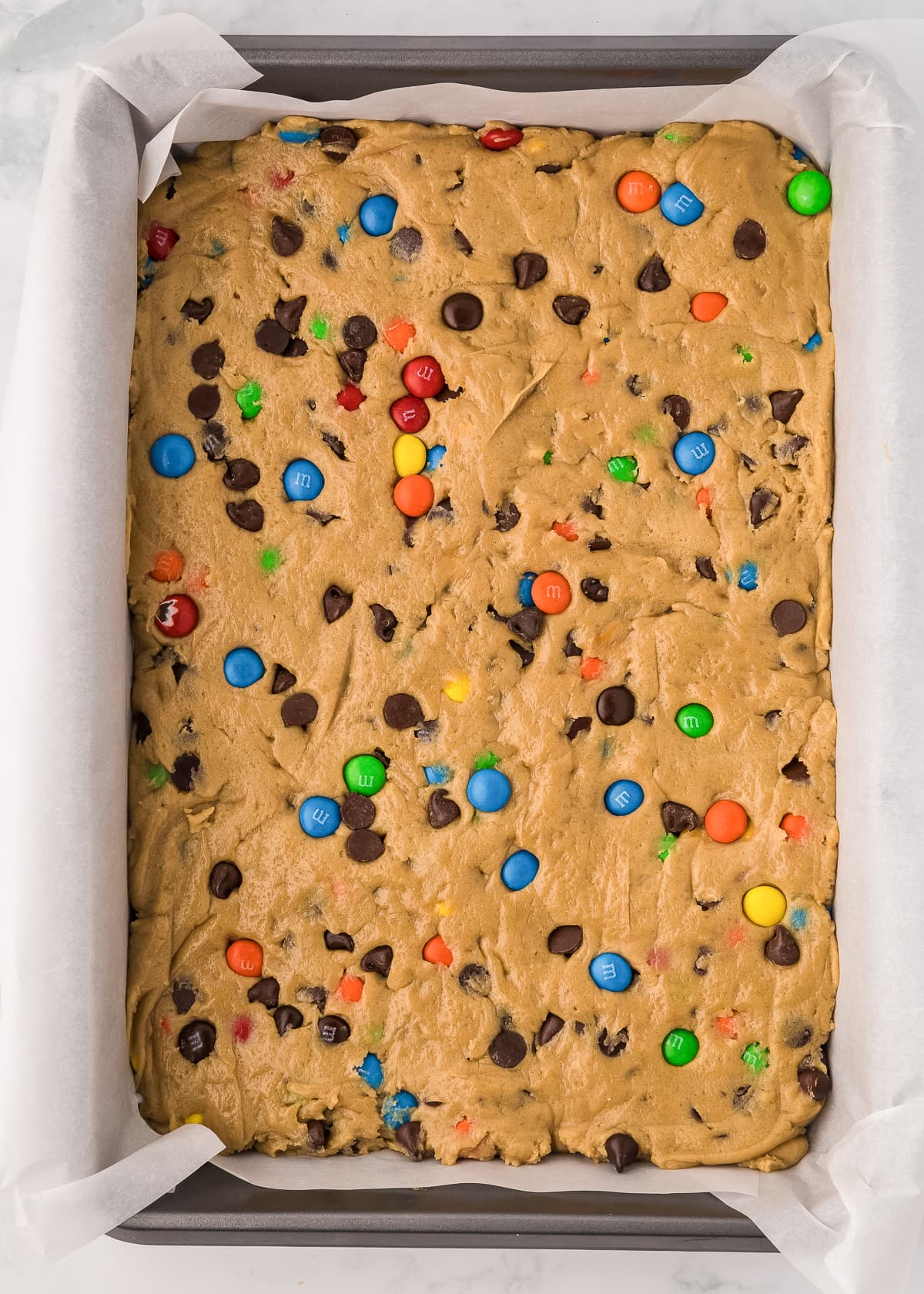 m&m cookie bar batter pressed into a baking pan.