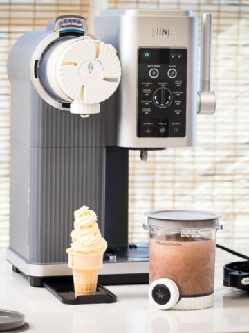 Ninja Swirl full review showing vanilla soft serve in an ice cream cone with a ninja swirl pint filled with chocolate soft serve ready to spin and the ninja swirl machine on the countertop.